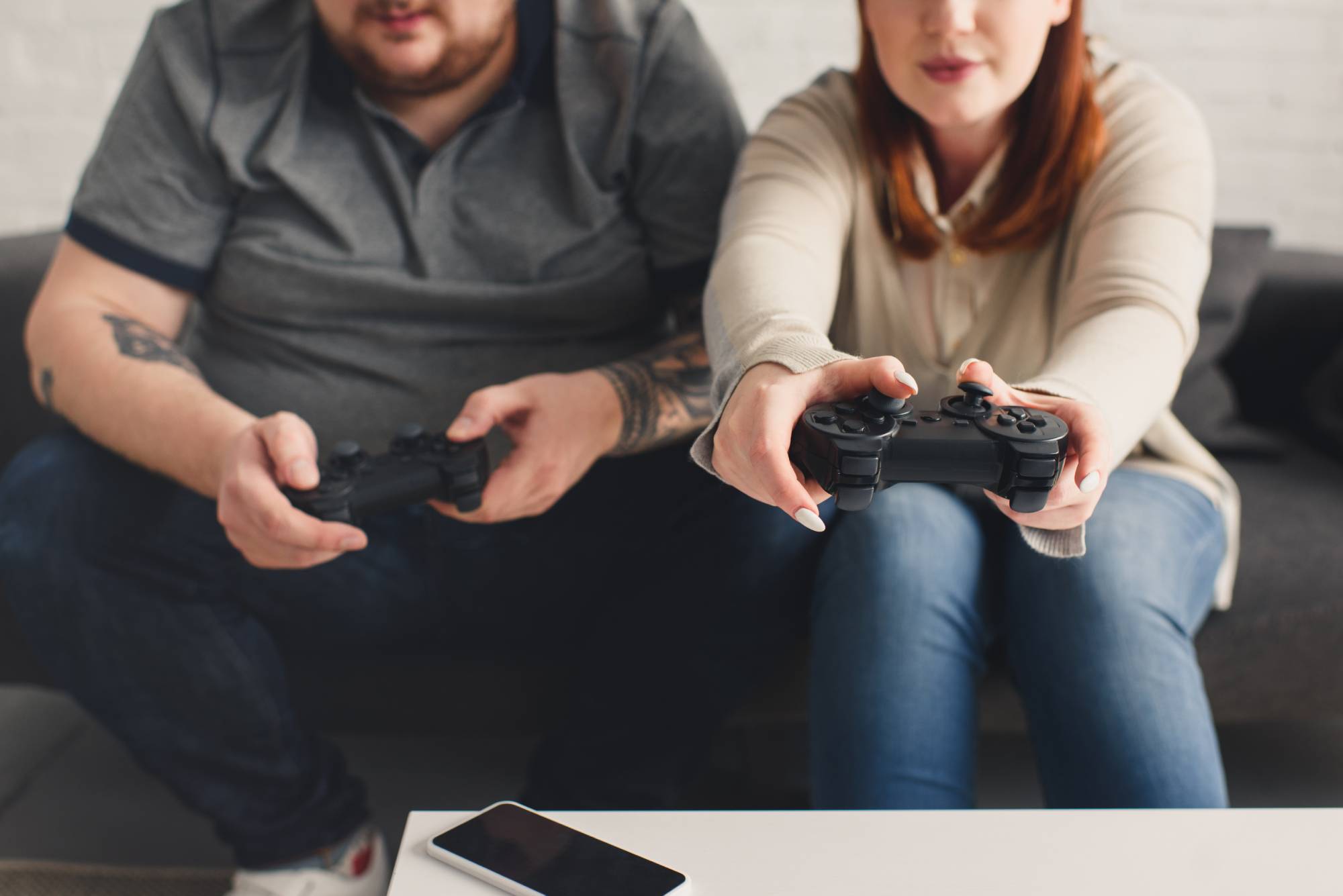 two gamers, male and female, sitting on the couch