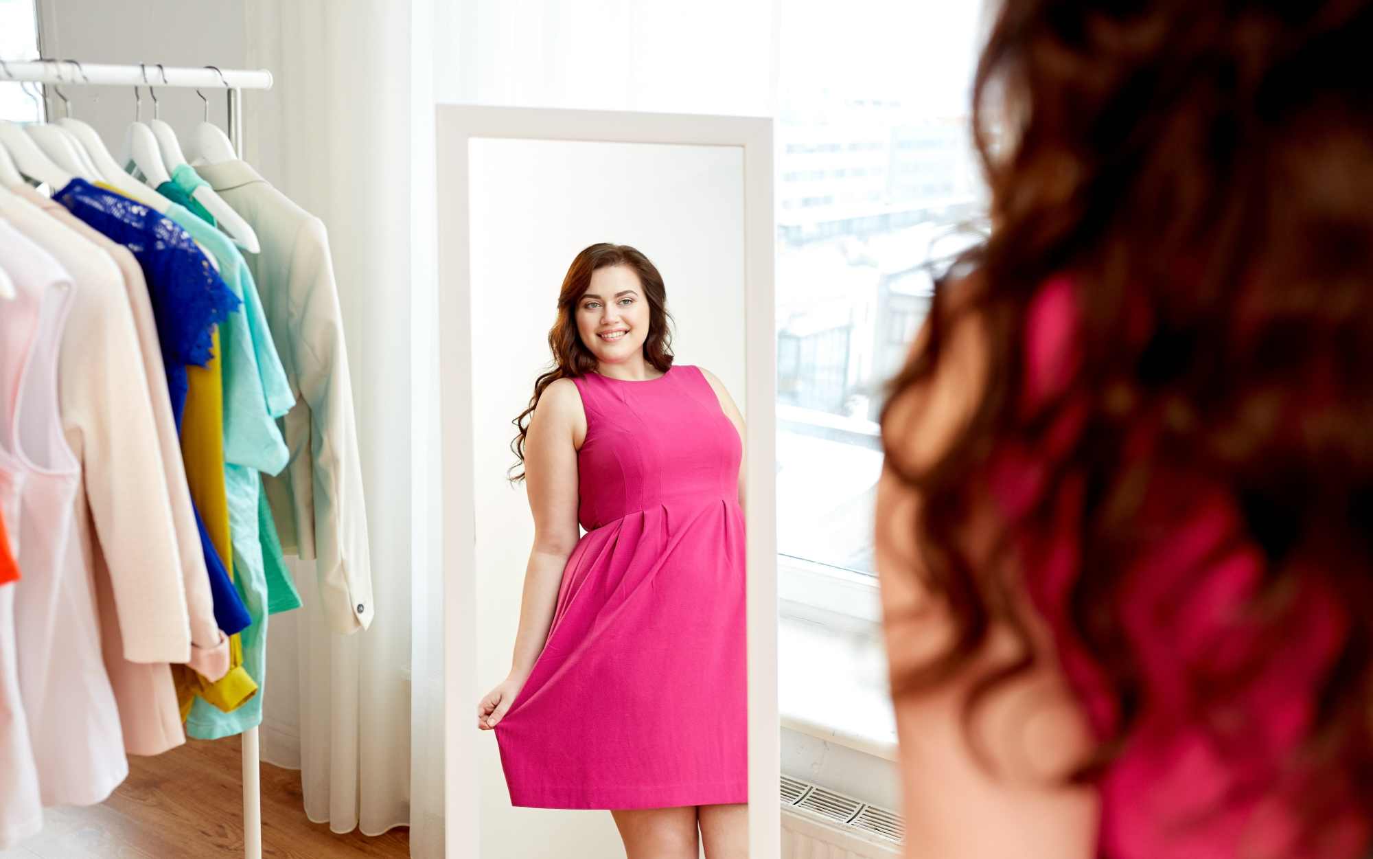 Happy woman trying on a plus sized pink dress